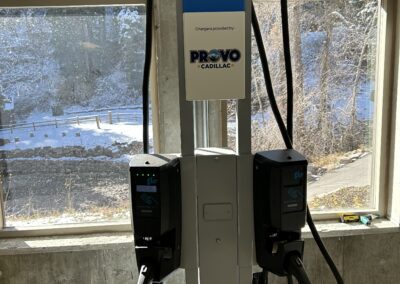 Two electric vehicle charging stations labeled "Ultium Charge 360," installed indoors with cables attached, sunlight streaming through windows behind them.